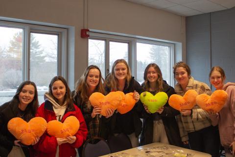 Students holding up stuffed heart pillows