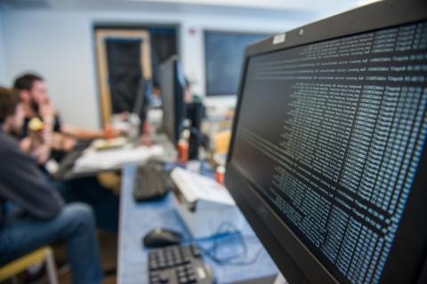 A large monitor in a UNH classroom showing rows of code and data
