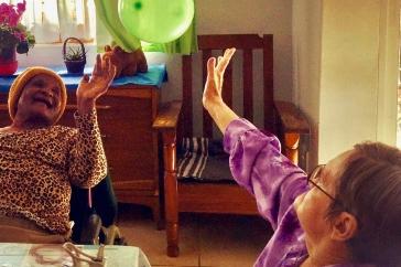 两个老妇人，一个白人，一个黑人，扔一个绿色的气球